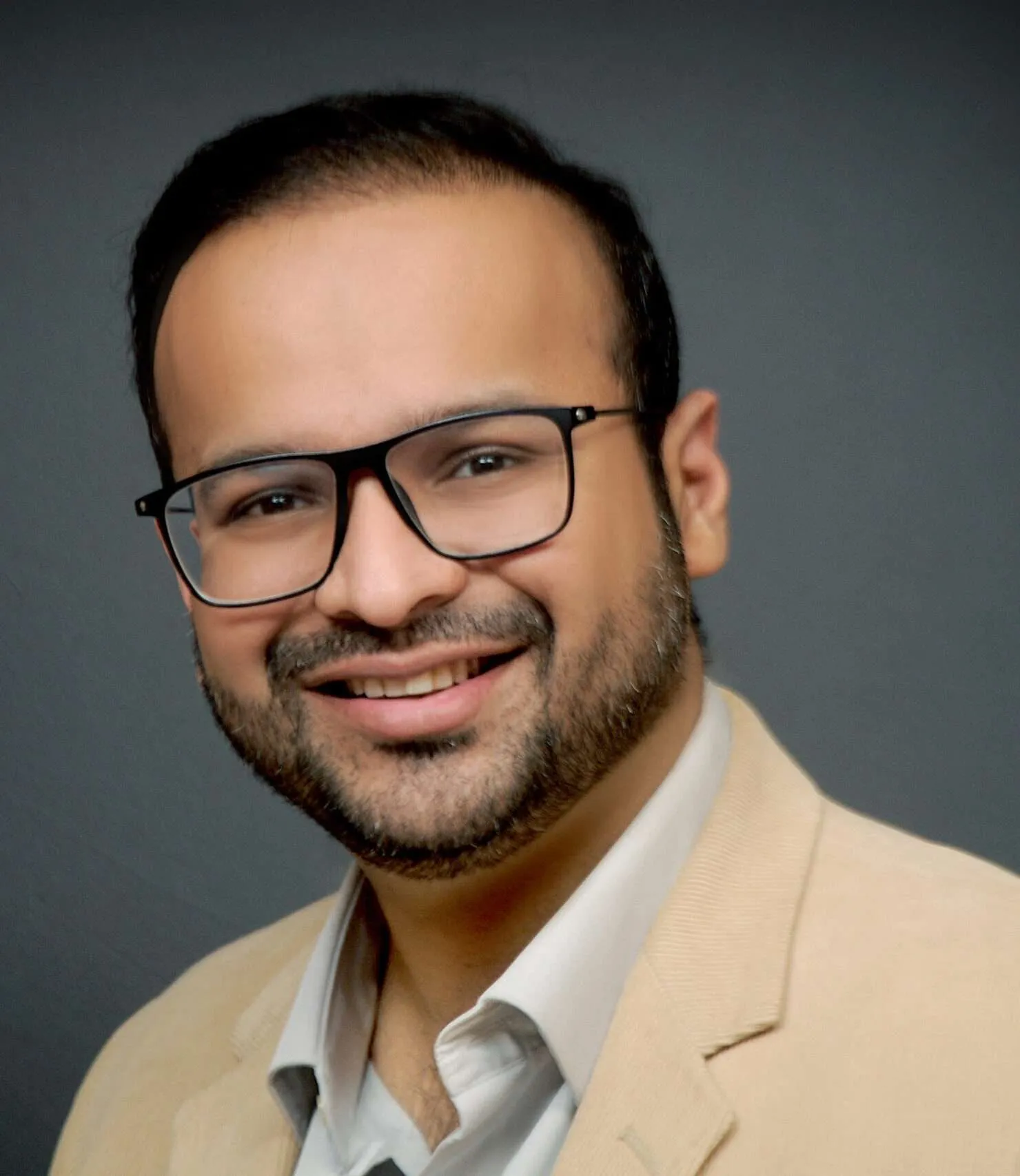 Dr-Mohit-Saraogi-scaled-e1695799208906 - Saraogi Hospital Smiling older man in a black suit, white shirt, and striped tie; wearing glasses for a professional portrait.